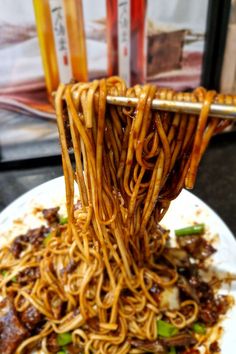 noodles being lifted from a plate with chopsticks