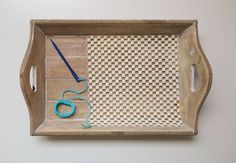 a wooden tray with scissors and yarn on it sitting on a white wall next to a pair of scissors