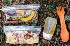 two plastic bags filled with food sitting on the ground next to an orange utensil