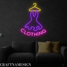 a neon sign that says clothing hanging on a wall next to a couch in a living room