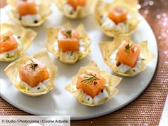 a white plate topped with small appetizers on top of a cloth covered table