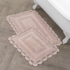 two pink rugs sitting on the floor next to a bath tub