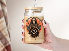 a person holding a glass jar with a skeleton on it and a straw in one hand