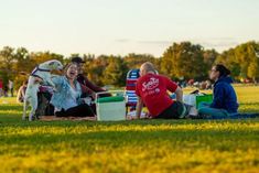 some people sitting on the grass and one is holding a dog