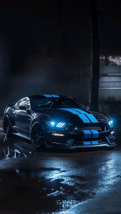 a black and blue sports car parked on the side of a road in the dark