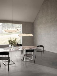 a dining table with four chairs in front of a window and a vase on the floor