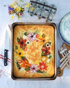 a baking dish with flowers painted on it next to utensils and other items