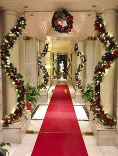 a red carpeted hallway decorated with christmas wreaths and garlandes on either side