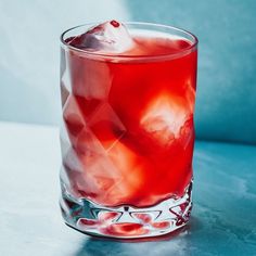 a close up of a drink in a glass on a table with ice cubes