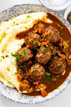 meatballs, mashed potatoes and gravy in a blue and white bowl