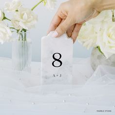 a person holding a card with the number eight on it and flowers in vases