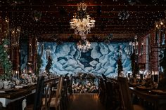 a dining room filled with lots of tables and chandelier hanging from the ceiling