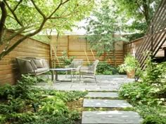 a small garden with stepping stones leading up to the deck and seating area for two