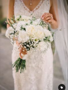 a bride holding a bouquet of white flowers