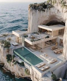 an aerial view of a house in the middle of the ocean with cliffs surrounding it