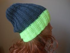 a close up of a person wearing a knitted hat with green and blue stripes