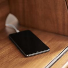 a black cell phone sitting on top of a wooden desk next to a white mouse