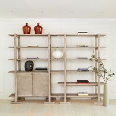 an empty room with shelves and vases on the wall next to eachother