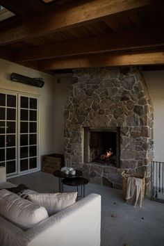 a living room with a stone fireplace and white couches