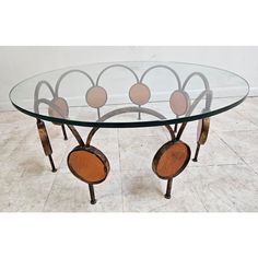 a glass and metal table with circles on the top, sitting on tile flooring