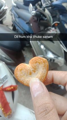 a person holding a heart shaped pastry in front of a scooter with the caption, dill hum kha chuke sanam