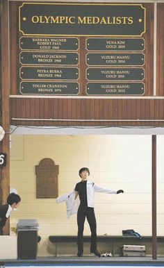 two people standing on top of a swimming pool in front of a sign that says olympic medals