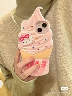 a woman holding an ice cream phone case with hello kitty on the front and pink icing on the back