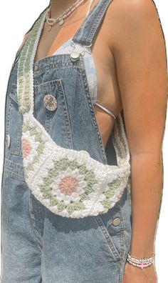 a woman wearing overalls with a crochet belt around her waist and holding onto an object