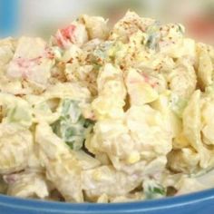 a blue bowl filled with pasta salad on top of a table