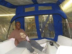 a man sitting on the edge of a boat in a room filled with blue tarps