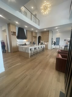 a large open floor plan living room and kitchen area with wood floors, white walls and ceiling lights