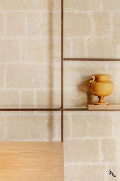 a yellow vase sitting on top of a wooden shelf