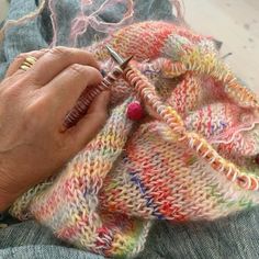 an older woman is knitting with her hands on the end of a piece of yarn