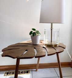 a wooden table with a lamp and potted plant on it