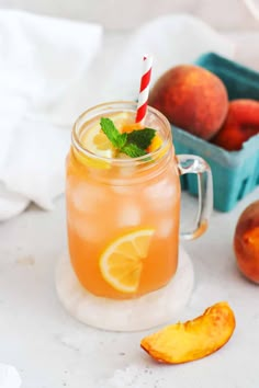 two mason jars filled with peaches and mint on top of a table next to apples