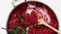 a pot filled with beet and spinach next to a wooden spoon in it