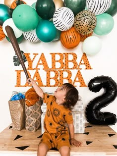 a young boy sitting on top of a table holding a baseball bat