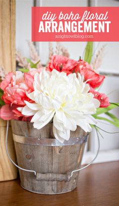 a bucket filled with white and red flowers on top of a wooden table next to a wall