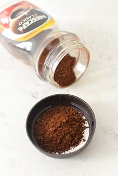 the ground coffee is in a small bowl next to it's container on the counter