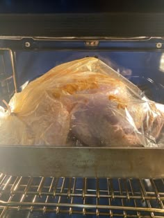 an uncooked turkey in the oven wrapped in plastic