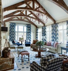 a living room filled with furniture and a chandelier hanging from the ceiling in front of two windows