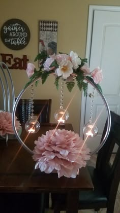 a table topped with a vase filled with pink flowers and hanging from the top of it