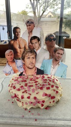 a birthday cake with the faces of two men and one woman on it in front of a window