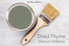 a paint can with a brush next to it on a white wooden background that says, dried thyme sherwin williams