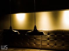 three lights hanging from the ceiling in a dimly lit room with couches and pillows