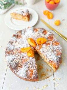 a cake with slices taken out of it sitting on a table next to some oranges