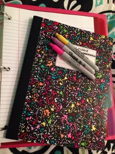 a notebook with two pens on top of it