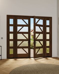 an open wooden door with glass panels in the middle of a living room, overlooking a field