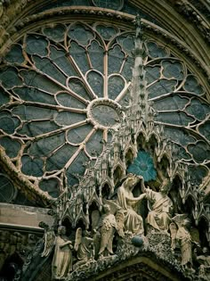 an ornate window with statues in front of it on the side of a church building