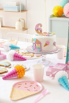 a table topped with a cake covered in icing next to cupcakes and other decorations